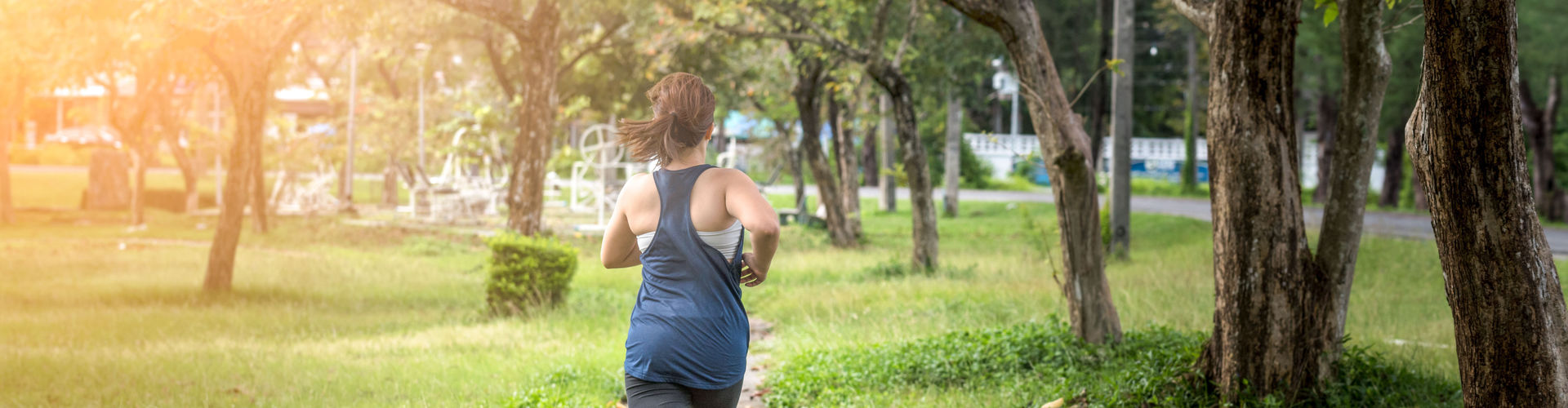 Eine Frau joggt durch den Park. Rückansicht