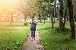 Eine Frau joggt durch den Park. Rückansicht