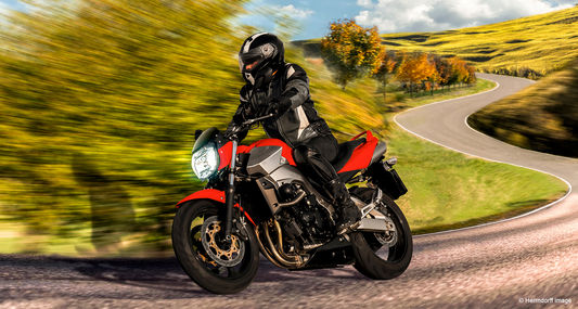 Person fährt mit Motorrad schnell um eine Kurve.
