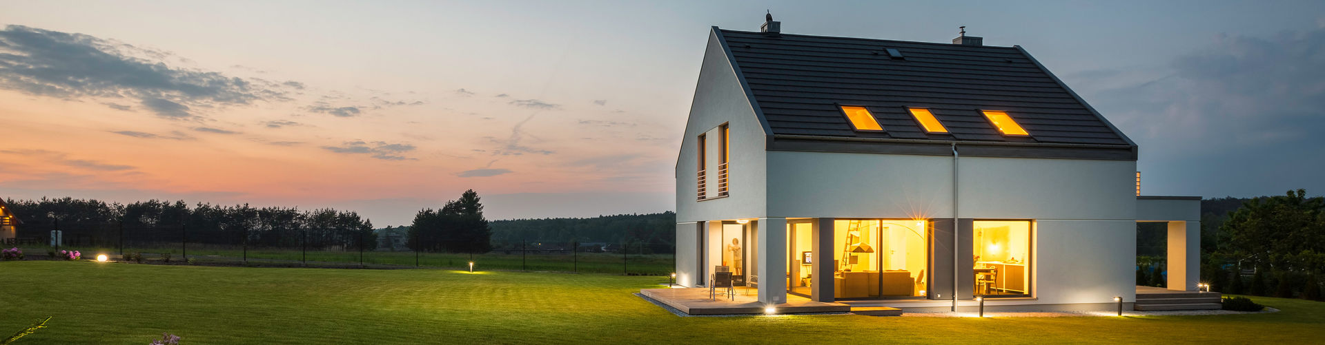 Ein hell beleuchtetes Haus auf einer großen Rasenfläche