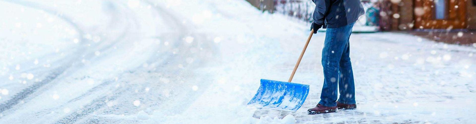 Ein Mann raeumt den Schnee vor dem Haus als Schutz vor Haftpflichtschaeden. 