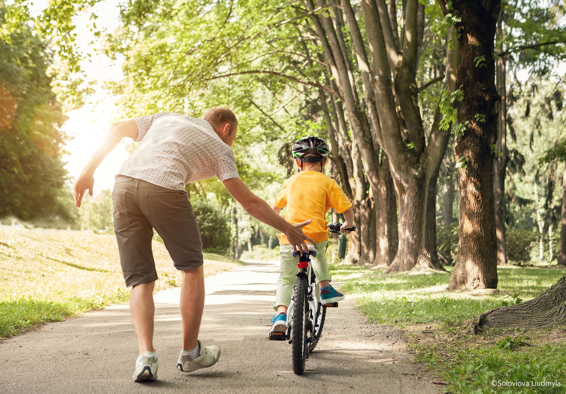 Vater hilft seinem Sohn beim Fahrrad fahren.
