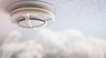 Rauchmelder hängt an der Decke und Rauch kommt auf ihn zu.