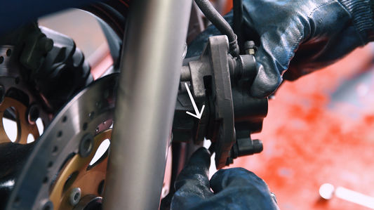 Person tauscht Bremsscheibe eines Motorrads.
