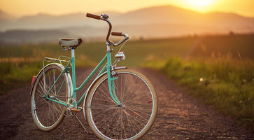 Fahrrad ist auf dem Weg vor einem schönen Sonnenuntergang geparkt.