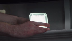 Eine Person hält ein leuchtendes Objekt in der Hand.