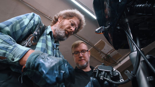 Werkstattmeister und Kunde schauen von oben auf sein Motorrad.