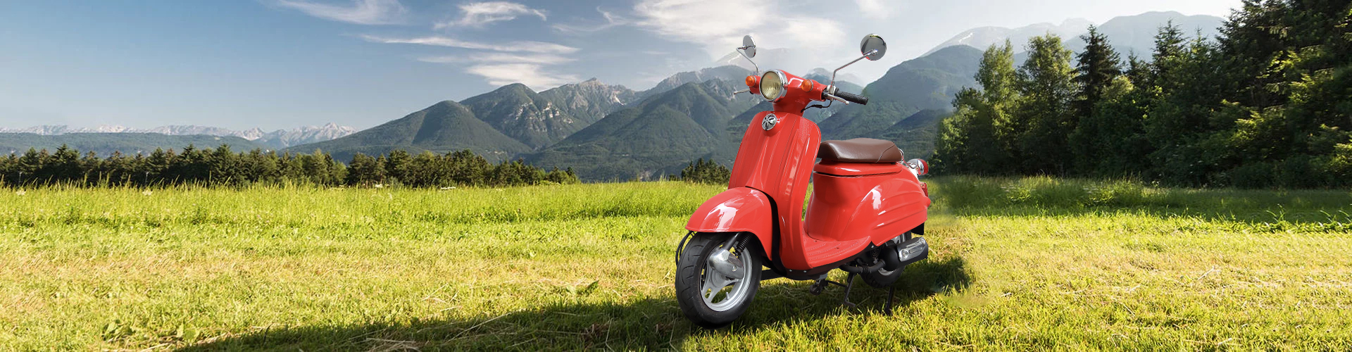 Rotes Moped auf einem Feld vor einer Bergkulisse.