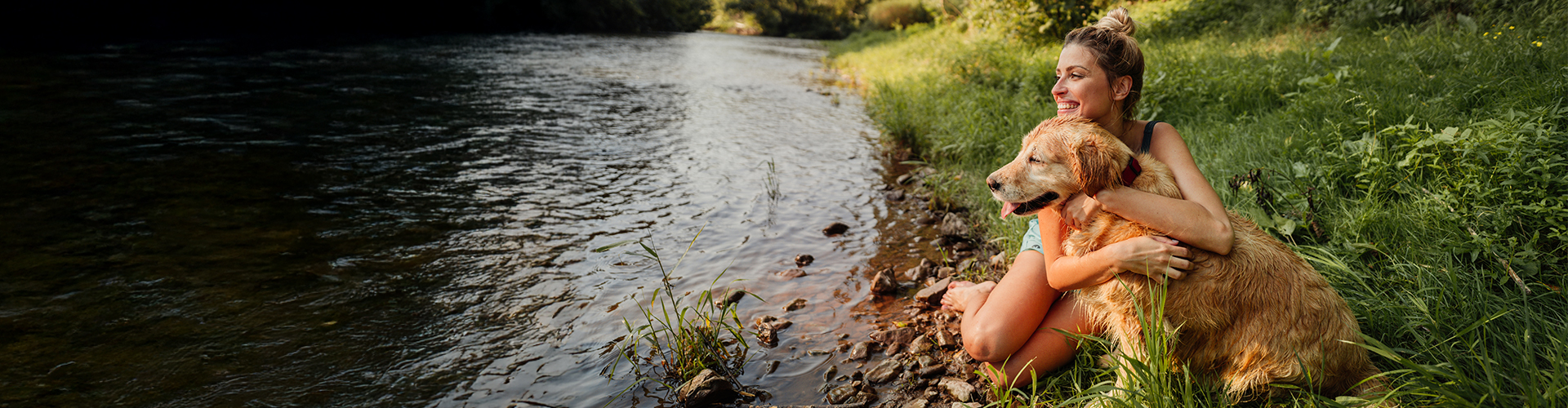 Golden Retriever- Hund mit Frau am Kuscheln an einem Fluss 